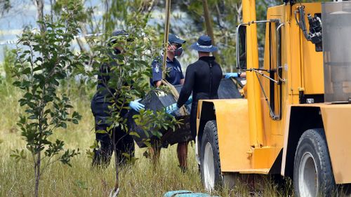 Police use a crane to retrieve a metal box from a dam at the scene where two bodies were found in Kingston last February. (AAP)