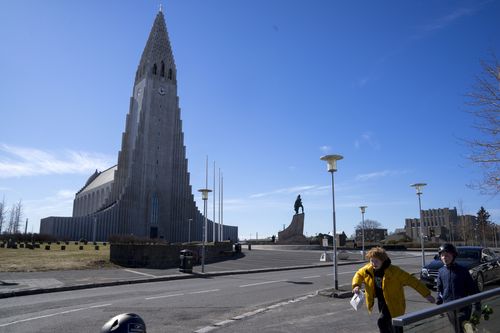 In this photo taken on Wednesday, April 29, 2020, two local boys walk past the the empty plaza of Hallgrimskirkja Church, a popular tourist destination in downtown Reykjavik, Iceland.