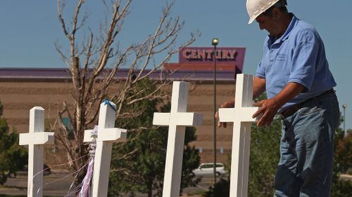 Greg Zanis placing two of the twelve crosses he made for a makeshift memorial to the victims of a mass shooting at the Century 16 movie theatre on July 22, 2012 in Aurora, Colorado. (AFP)