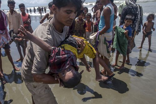 A man shakes a Rohingya Muslim boy while trying to revive him after the boat he was travelling in capsized. (AP)