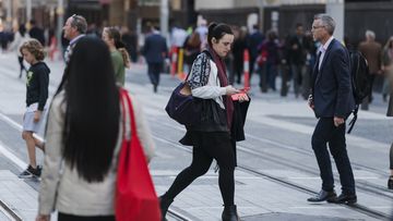A woman uses a phone in a crowd on George Street, Sydney