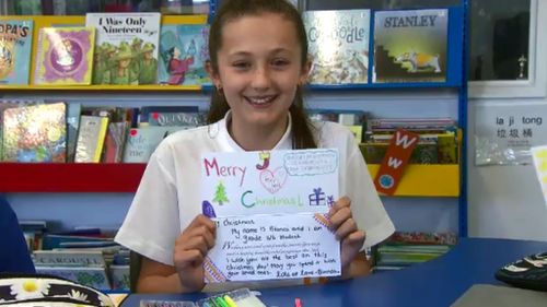 A student proudly holds her colourful card. (9NEWS)