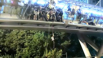Protesters use a rope to lower themselves from a pedestrian bridge to waiting motorbikes in order to escape from Hong Kong Polytechnic University and the police in Hong Kong
