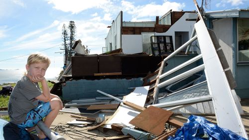 Tarn Smith, 7, is seen in front of his family's damaged home in John St, Yeppoon. (AAP)