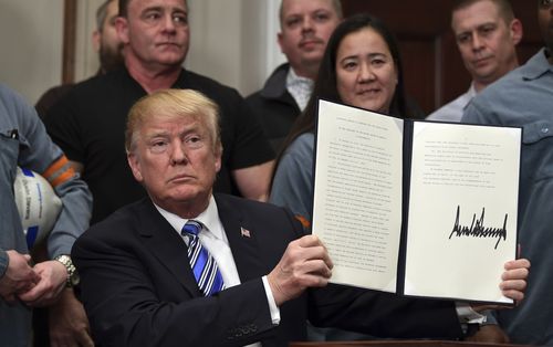 President Donald Trump holds up a proclamation on aluminum during an event. (AAP)