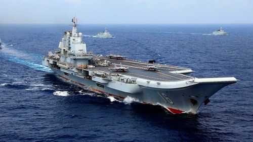 Two J-15 fighter jets of the PLA (People's Liberation Army) Navy prepare to take off from China's aircraft carrier, The Liaoning, followed by destroyers and frigates during a naval exercise in the western Pacific