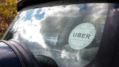 Janela traseira de um carro Uber preto com o adesivo Uber branco no vidro.