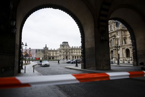 Police officers stand guard outside the Louvre Museum as people are evacuated after it received a written threat, in Paris, Saturday Oct. 14, 2023.  