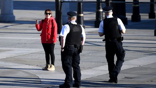 British policemen speak with a woman during tough new COVID-19 movement restrictions in the UK.