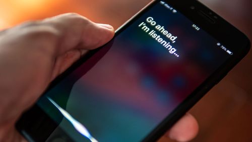 Person holding Apple phone uses the 'Hey Siri' command