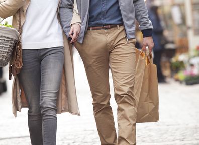 Couple walking down the street holding shopping bags.