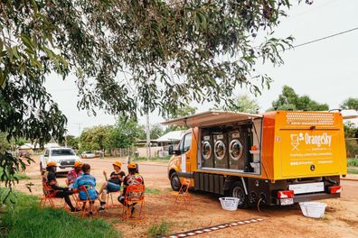 An OrangeSky van, with volunteers and locals chatting out front.