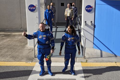NASA astronauts Butch Wilmore, left, and Suni Williams leave the operations and checkout building