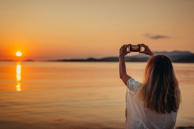 Woman using her smartphone on the beach