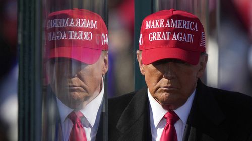 FILE - Republican presidential nominee former President Donald Trump is reflected in the bullet proof glass as he finishes speaking at a campaign rally in Lititz, Pa., Nov. 3, 2024. (AP Photo/Matt Rourke, File)