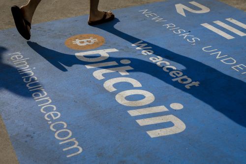 Person walks over Bitcoin sign