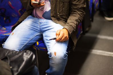 Essen, Germany - September 17, 2015: Immigrant man with mobile and e-cigarette is sitting in subway train in Essen. Man is watching mobile.
