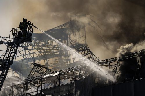 Firefighters work as smoke rises out of the Old Stock Exchange in Copenhagen, Denmark, Tuesday, April 16, 2024.