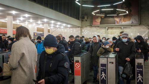 Les navetteurs passent par les barrières tarifaires de la station de métro Lukyanivska à Kiev, en Ukraine.