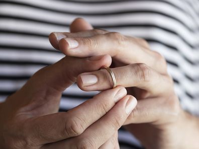 Woman taking off wedding ring.