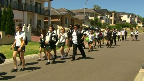 The students carried flowers to the home, and laid them upon the fence. (9NEWS)