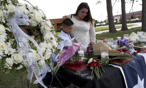 Kaley Gates and her sons Brayden, Carson and Mason look over notes and flowers left at the memorial in Santa Fe. Picture: AP