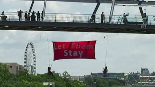 Protesters dangled a #LetThemStay banner from Brisbane's Story Bridge. (9NEWS)
