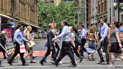 Sydney, Australia - November 12, 2015: People crowd crossing street in central Sydney. Landmark in background, shopping center to the left.