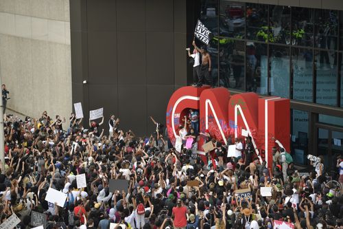 Demonstrators paint on the CNN logo during a protest in Atlanta, Georgia.