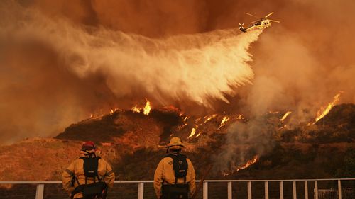 Os bombeiros observam enquanto a água cai no incêndio de Palisades em Mandeville Canyon no sábado, 11 de janeiro de 2025, em Los Angeles. (Foto AP/Jae C. Hong)