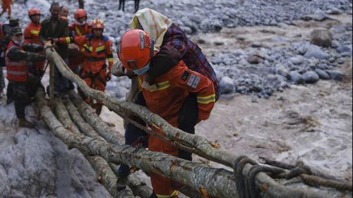 In this photo released by Xinhua News Agency, rescuers carry a villager across a river following an earthquake in Moxi Town of Luding County, southwest China's Sichuan Province on Monday, Sept. 5, 2022. Dozens people were reported killed and missing in a 6.8 magnitude earthquake that shook China's southwestern province of Sichuan on Monday, triggering landslides and shaking buildings in the provincial capital of Chengdu, whose 21 million residents are already under a COVID-19 lockdown. (Cheng Xu