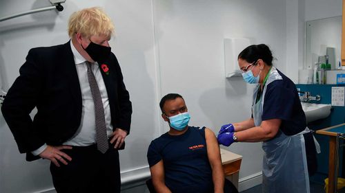 UK PM Boris Johnson supervises a vaccine administration.