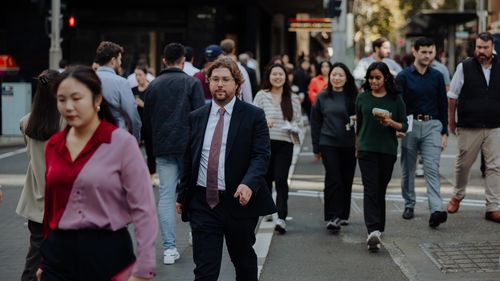 Pedestres e funcionários de escritório caminham pelo CBD de Sydney. 