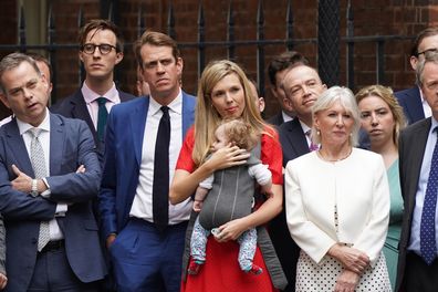 Carrie Johnson, the wife of British Prime Minister Boris Johnson, cradles their daughter Romy as she listens to him read a statement outside 10 Downing Street, London, formally resigning as Conservative Party leader, in London, Thursday, July 7, 2022. 