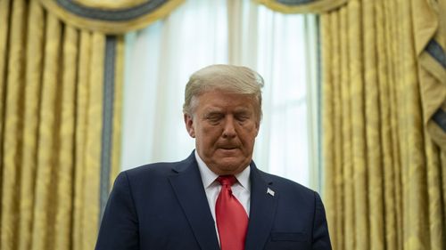 President Donald Trump listens during a ceremony to present the Presidential Medal of Freedom to former soccer coach Lou Holtz, in the Oval Office of the White House, Thursday, Dec. 3, 2020, in Washington.