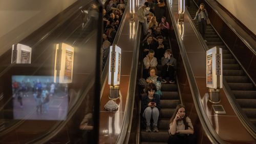 People sit on an escalator as they shelter in a subway station during Russian missiles attack on May 29, 2023 in Kyiv, Ukraine. 