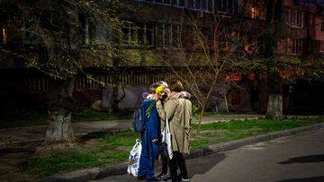 Three women embrace in a street in Kyiv after a Russian attack