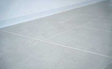 Close-up of tiled floor and a baseboard at the wall