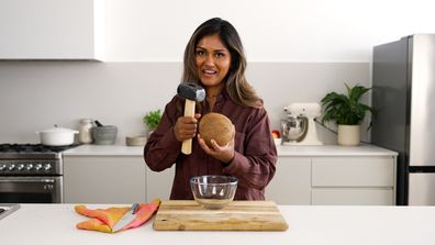 Image of Minoli De Silva uses a mallet to tap at each side of the coconut's shell.