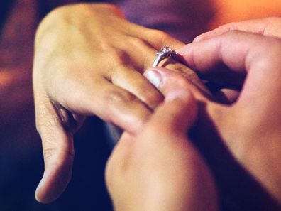 Man placing ring on woman's finger following proposal