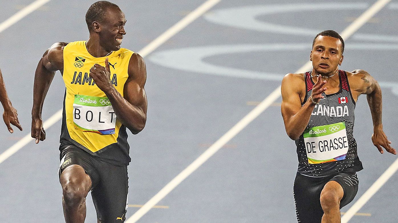 Usain Bolt smiles as he looks at Andre De Grasse in the Men&#x27;s 100 metre semifinal of the Rio 2016 Olympic Games