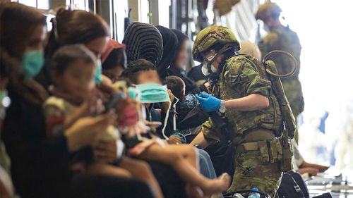 The RAAF Air Load Team assist evacuees into their seats on board the C-17A Globemaster II.