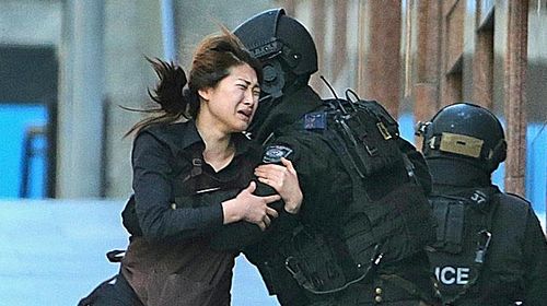 Jieun Bae runs to armed tactical response police officers for safety after she escaped from a cafe under siege at Martin Place in the central business district of Sydney, Australia. (Rob Griffith)