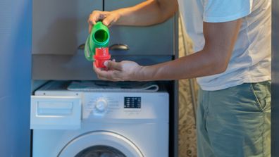 Man Pouring Liquid Detergent Gel Into Washing Laundry Machine At Home
