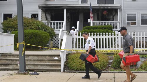 Investigators, front, remove boxes containing patient medications from the Gabriel House assisted living facility, behind, following a fire that resulted in multiple fatalities, in Fall River, Mass., Monday, July 14, 2025. (AP Photo/Steven Senne)