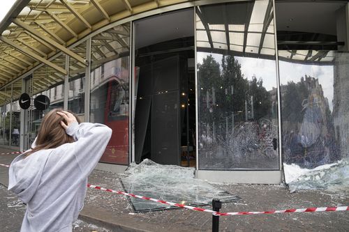 A woman reacts by damaged sports store after a third night of unrest, Friday, June 30, 2023 in Paris. 