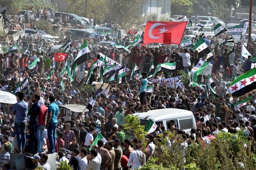Syrians from the rebel-held northern city of Idlib and its surrounding towns wave the flag of the opposition and chant slogans as they gather for an anti-government demonstration in a main square in Idlib on Friday.