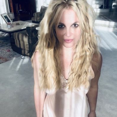 Britney Spears standing in beige dress looking directly at camera