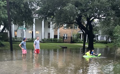 Australian BHP Billiton employee David Bryant (left) and his American friend Robert Sears survey a flooded street in his Houston neighbourhood. (AAP)