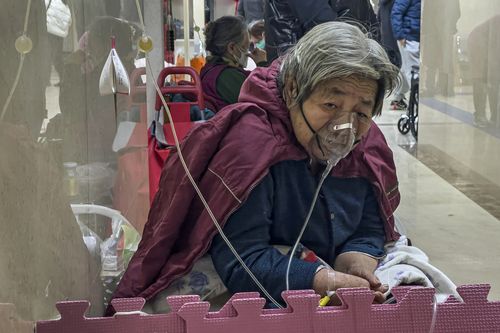 An elderly patient receives an intravenous drip while using a ventilator in the hallway of the emergency ward in Beijing, Thursday, Jan. 5, 2023. 